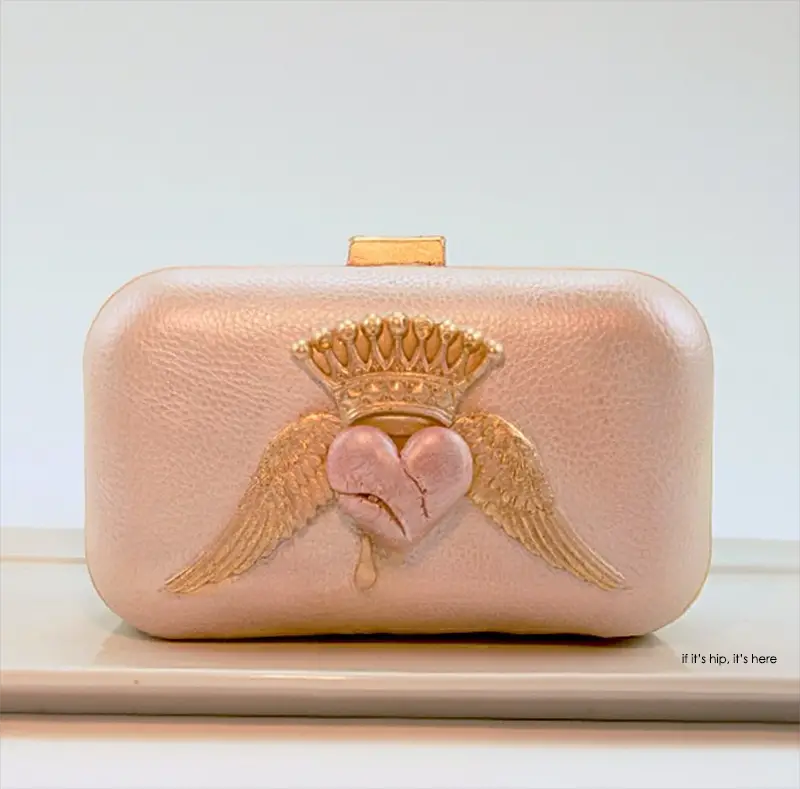 White chocolate clutch with pink heart, gold wings and crown. Sweetheart chocolate purse is hand painted with edible lustre dusts and filled with moist red velvet cake