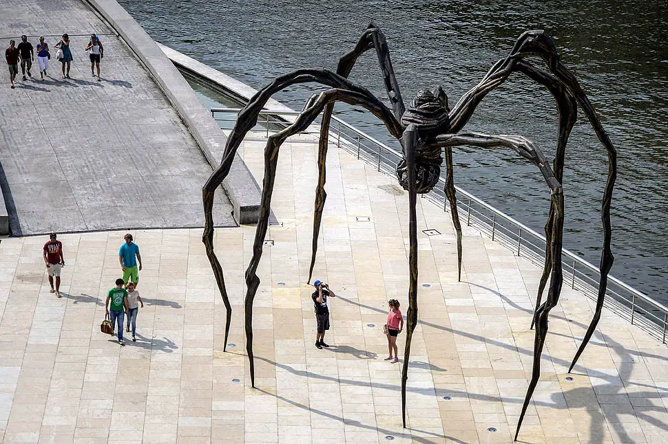 Pedestrians pass the "Spider Maman" steel sculpture by Louise Bourgeois on the waterside in Bilbao, Spain.