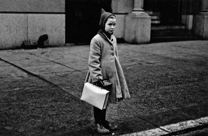 Diane Arbus, Girl with a pointy hood and white schoolbag at the curb, N.Y.C., 1957