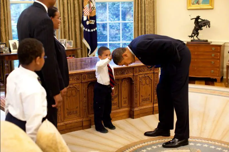 President Obama lets three year old Jacob Philadelphia touch his hair as his family watches