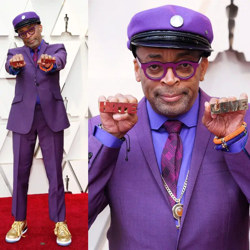 Spike Lee in his purple homage to Prince with Gold sneakers and Love/ Hate rings.