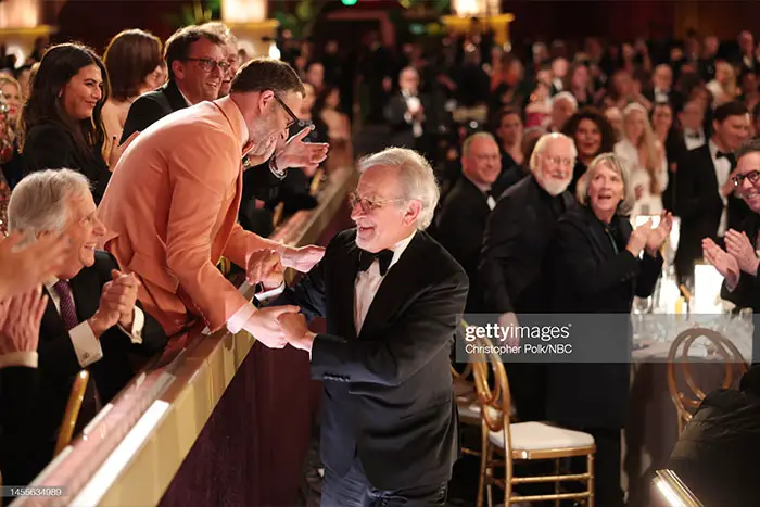 Seth Rogen congratulates Steven Spielberg as the director heads toward the podium.