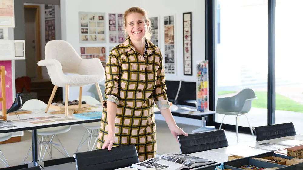 Llisa Demetrios, at the Eames institute, in a gallery, with designs and materials from the Eames collection, Kazam! Magazine